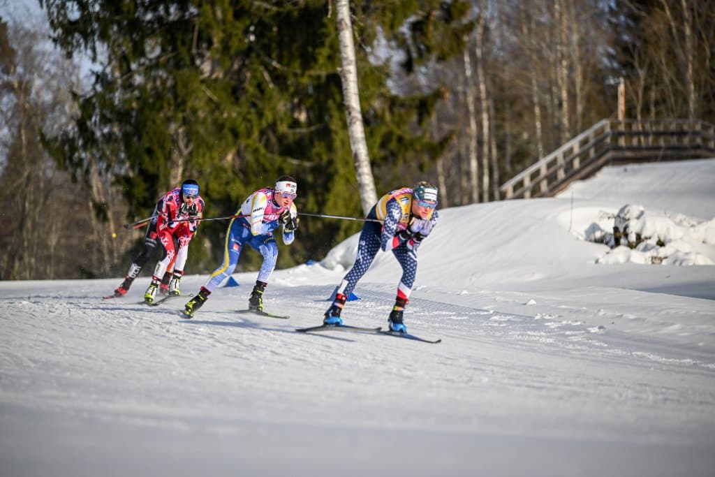 Three skiers in a tight pack cresting a rise in a distance race